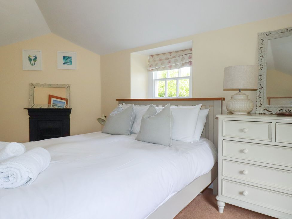 A bedroom with a bed and dresser at Trevethen Cottage in Crantock