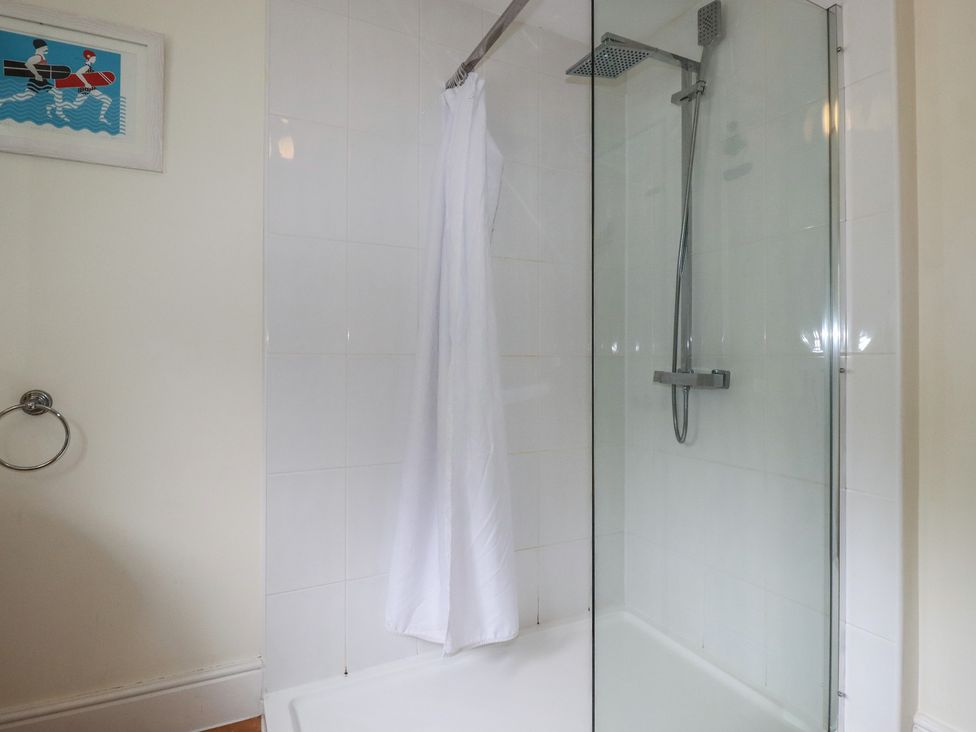 A shower enclosure with a curtain at Trevethen Cottage in Crantock