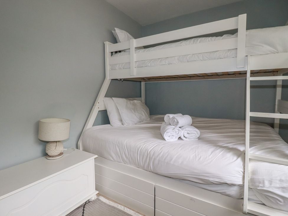 A bedroom with a bunk bed and a double bed at Trevethen Cottage in Crantock