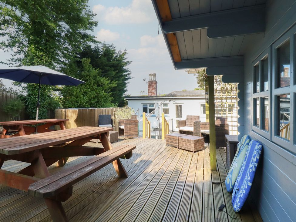 An outdoor deck with seating and a table at Trevethen Cottage in Crantock