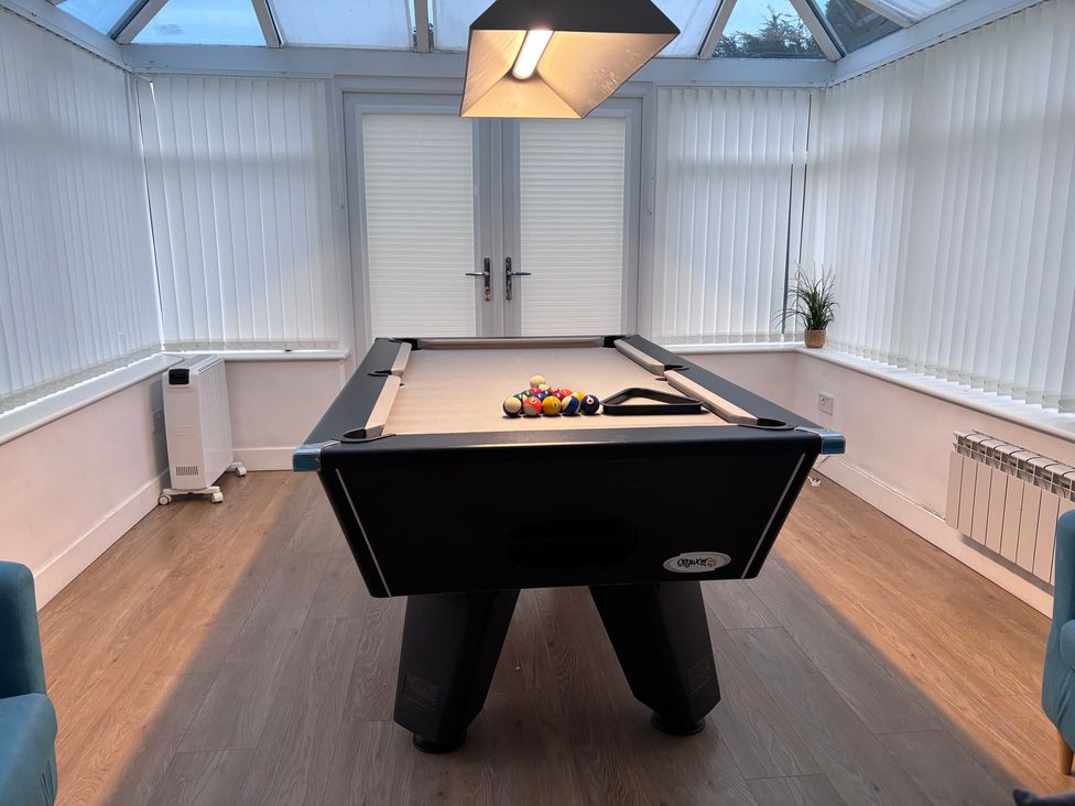 A pool table with balls under a light in a conservatory at Monarfon Amlwch