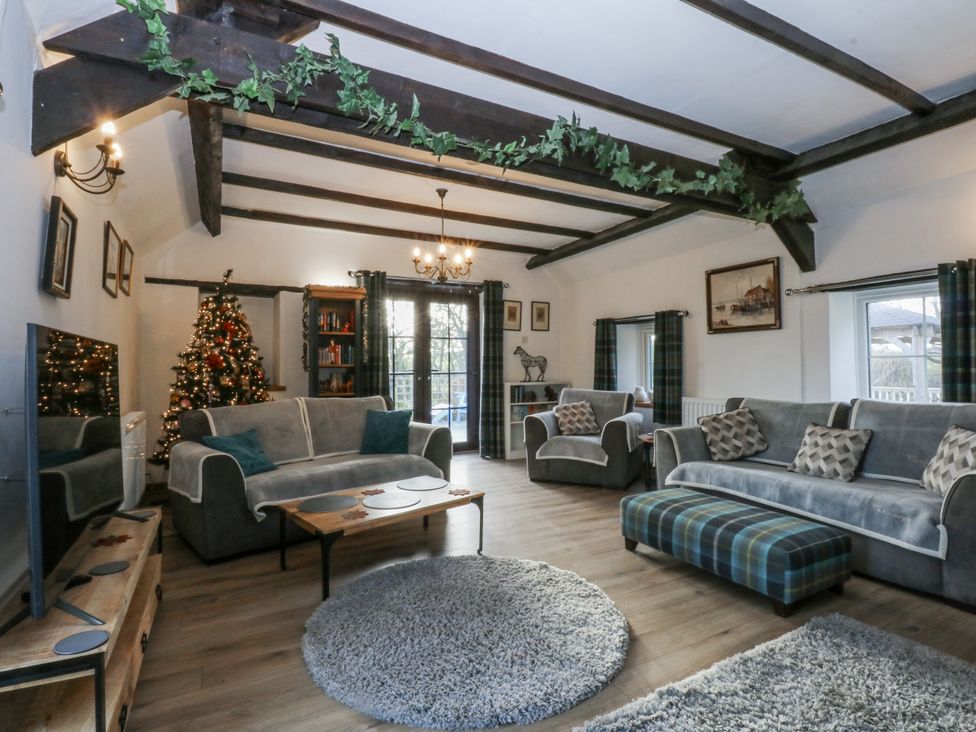A living room featuring a sofa, armchairs, and a Christmas tree at Ty Gwennol in Llanfaethlu