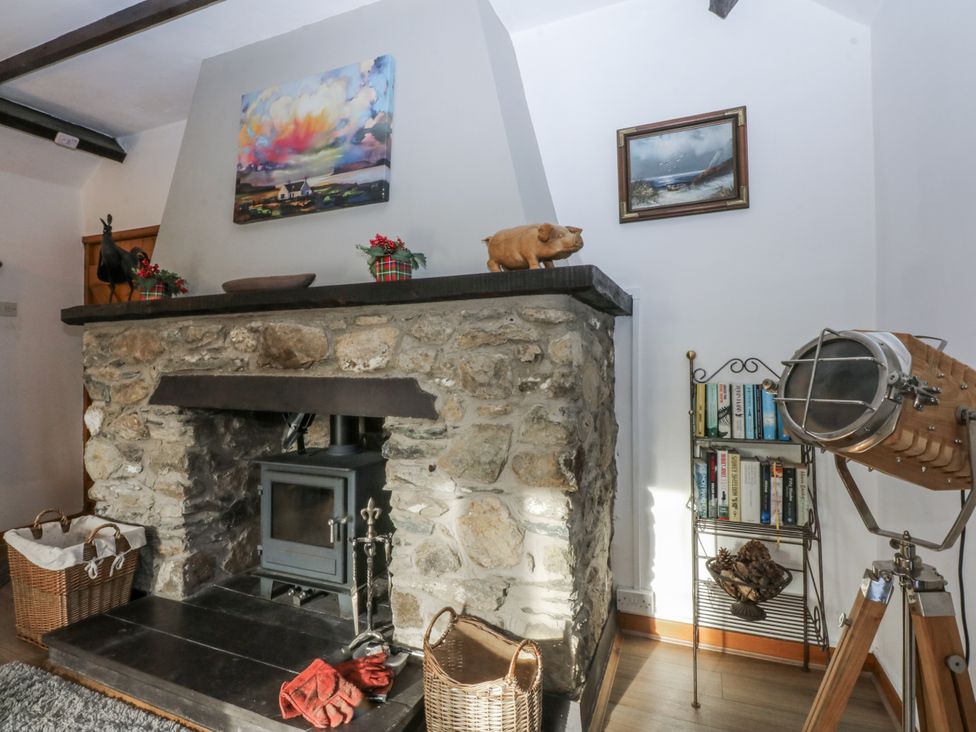 A living room with a stone fireplace and wooden stove at Ty Gwennol in Llanfaethlu