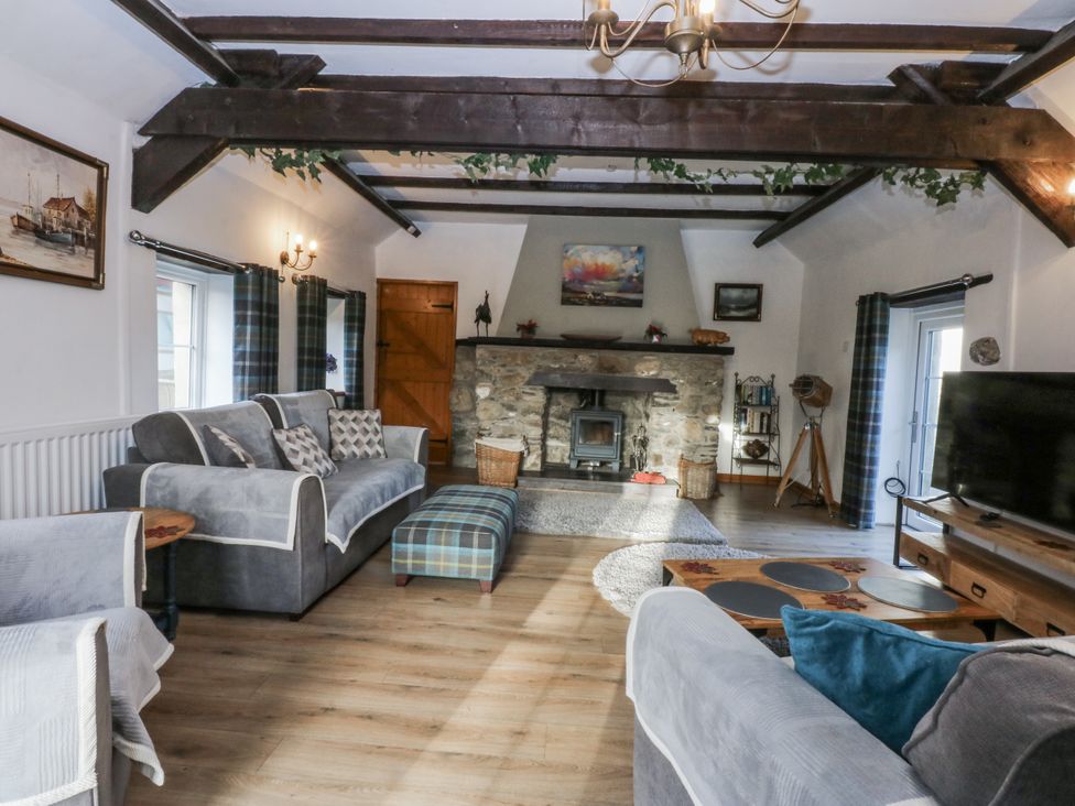 A living room with a fireplace and furniture at Ty Gwennol in Llanfaethlu