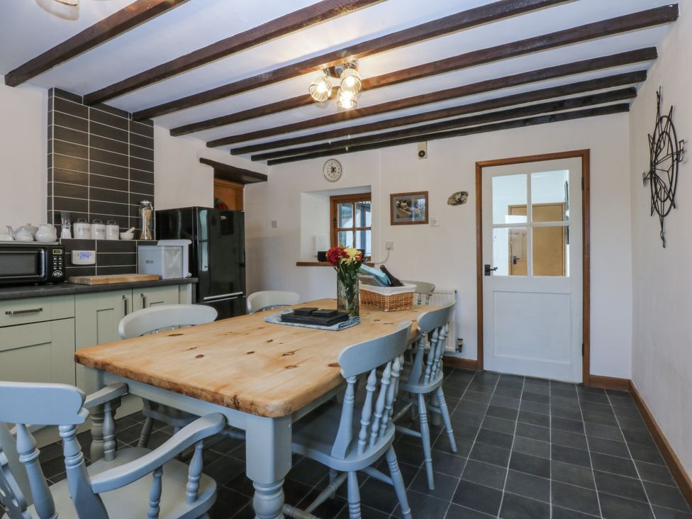 A kitchen with a dining table and appliances at Ty Gwennol in Llanfaethlu