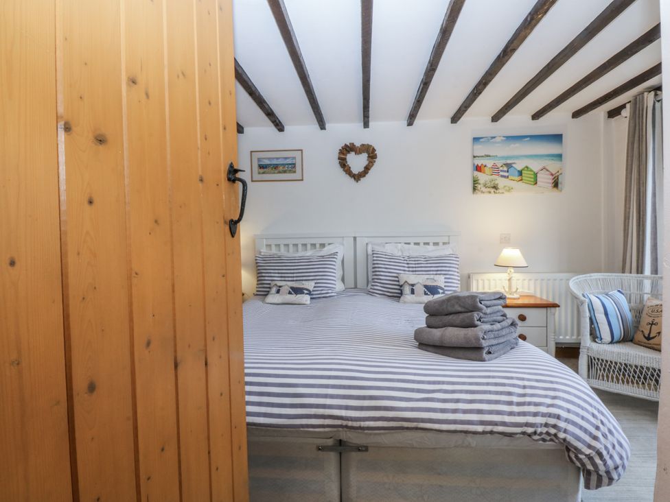 A bedroom with a striped bed and a chair at Ty Gwennol in Llanfaethlu