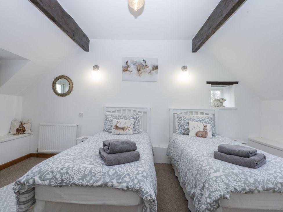 A bedroom with two beds and a mirror at Ty Gwennol in Llanfaethlu