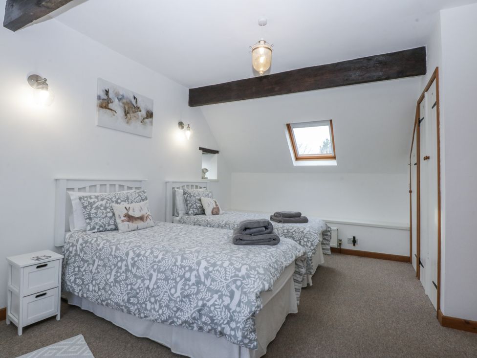 A bedroom with two beds and a window at Ty Gwennol in Llanfaethlu