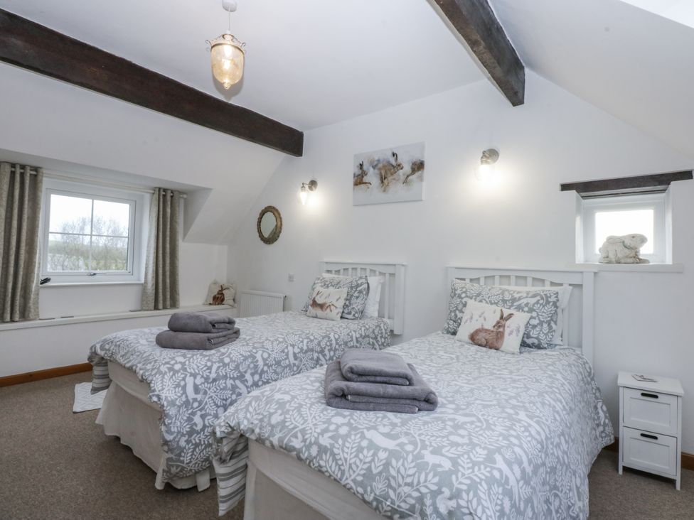A bedroom with two beds and window at Ty Gwennol in Llanfaethlu