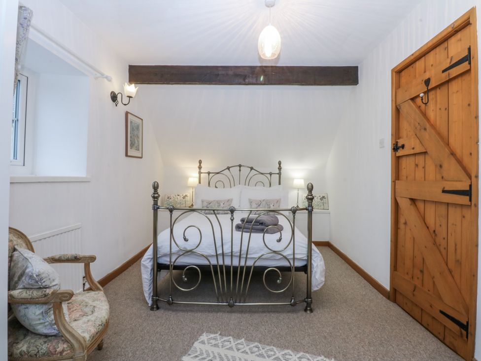 A bedroom with a bed and chair at Ty Gwennol in Llanfaethlu