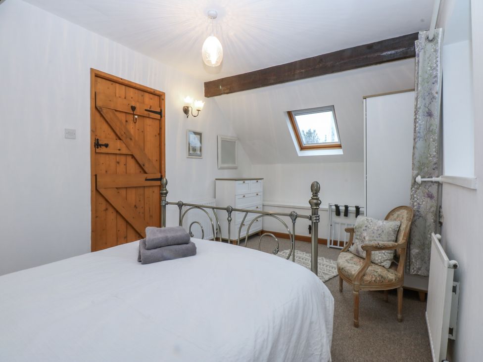 A bedroom with a bed and wooden door at Ty Gwennol in Llanfaethlu
