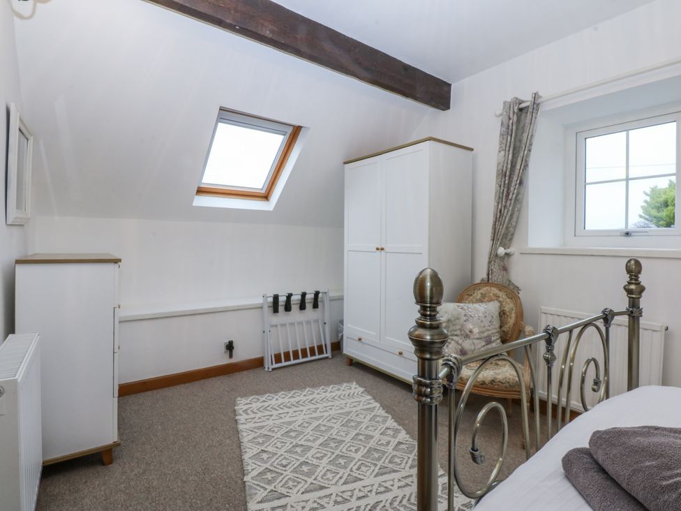 A bedroom with a bed, wardrobe, and chair at Ty Gwennol in Llanfaethlu