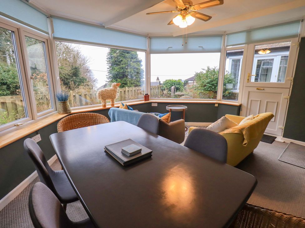 A conservatory with a table and chairs at Yewbarrow Cottage in Grange-Over-Sands