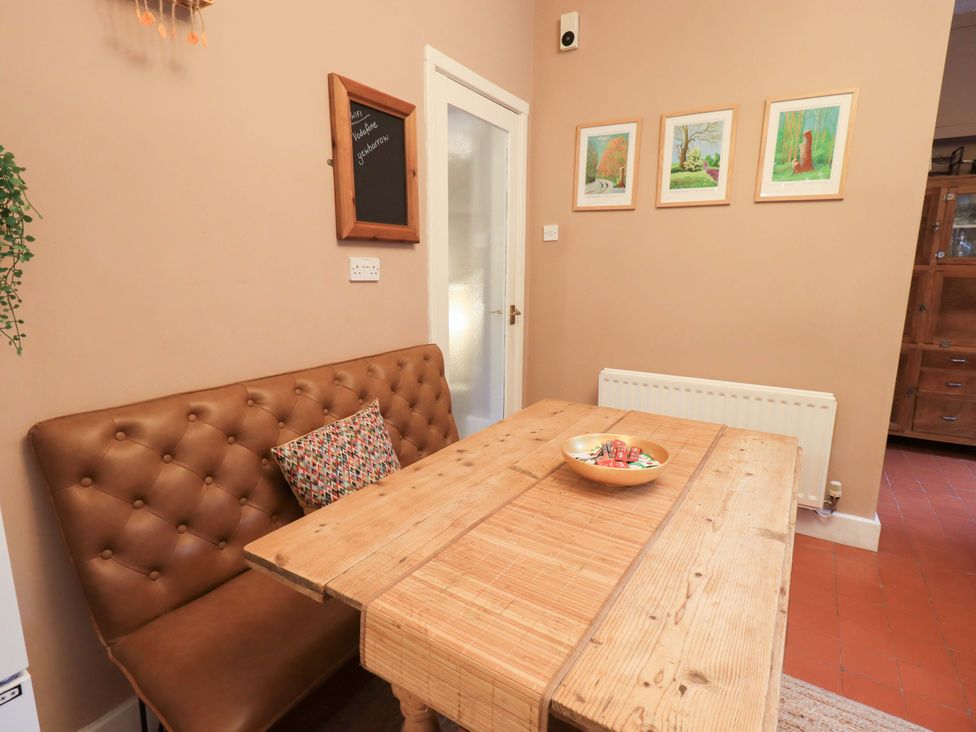 A dining room with a table and bench seating at Yewbarrow Cottage in Grange-Over-Sands