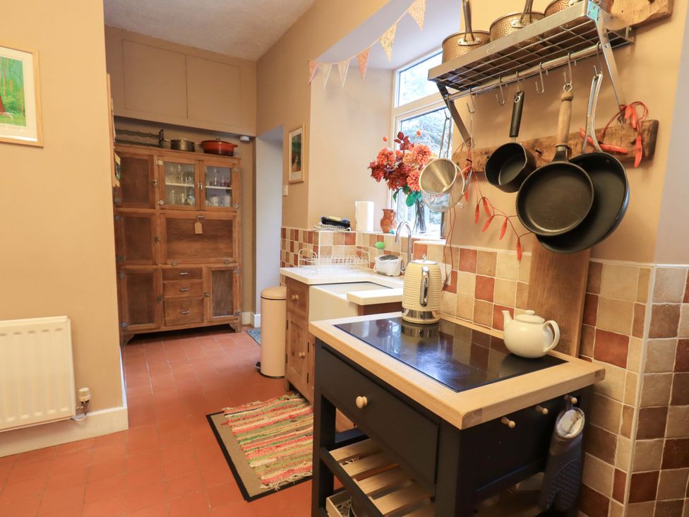 A kitchen with a sink, stove, and storage cabinets at Yewbarrow Cottage in Grange-Over-Sands