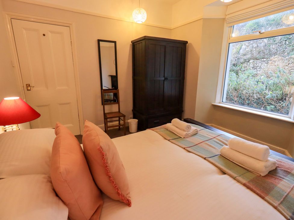 A bedroom with a bed, wardrobe, and window at Yewbarrow Cottage in Grange-Over-Sands
