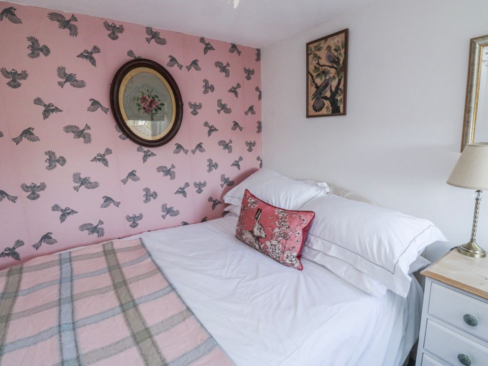 A bedroom with a bed and wall art at 3 Rock Cottages Kingston