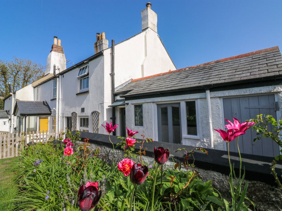 An outdoor area with flowers and a house at 3 Rock Cottages Kingston