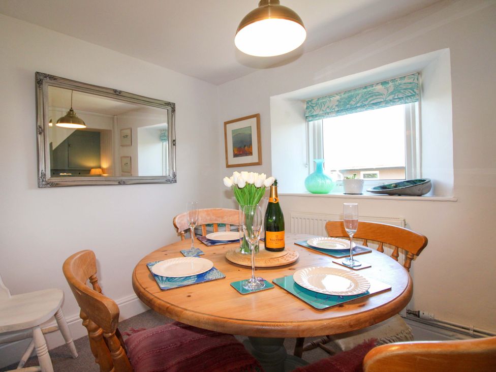 A dining room with a round table set for a meal at 3 Rock Cottages in Kingston