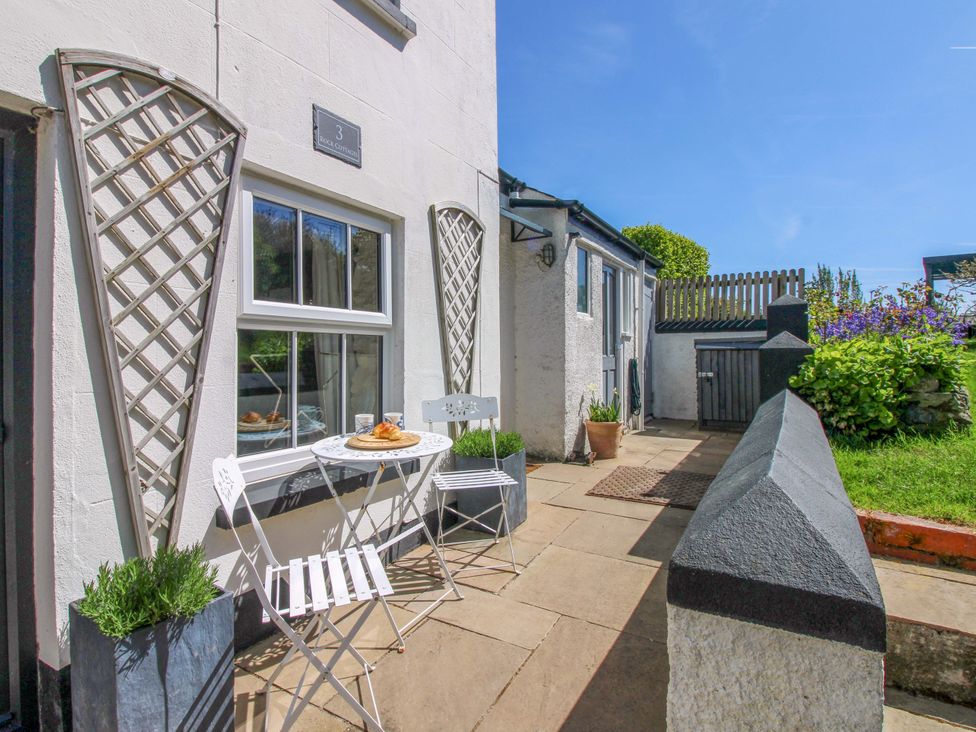 An outdoor patio area with a table and chairs at 3 Rock Cottages Kingston