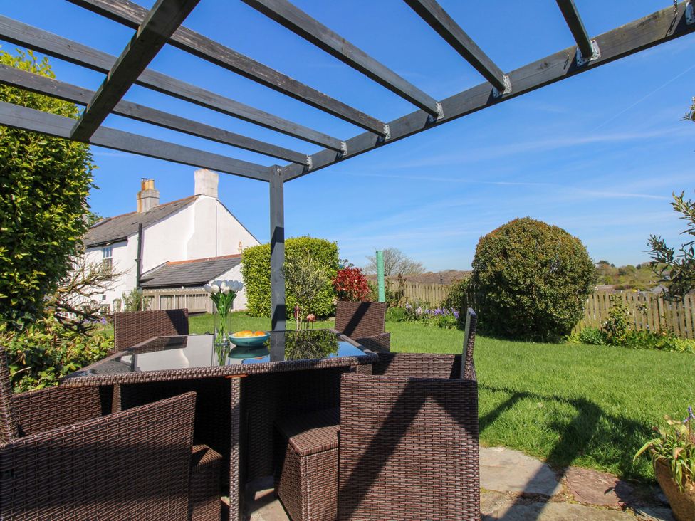 A garden with a table and chairs under a pergola at 3 Rock Cottages Kingston