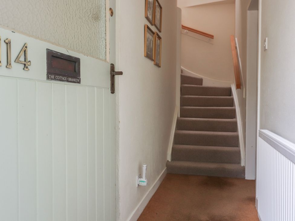 A hallway with a staircase and framed pictures at Branklyn Garden Cottage in Perth
