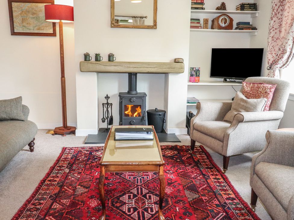 A living room with a fireplace, armchair, and sofa at Branklyn Garden Cottage in Perth