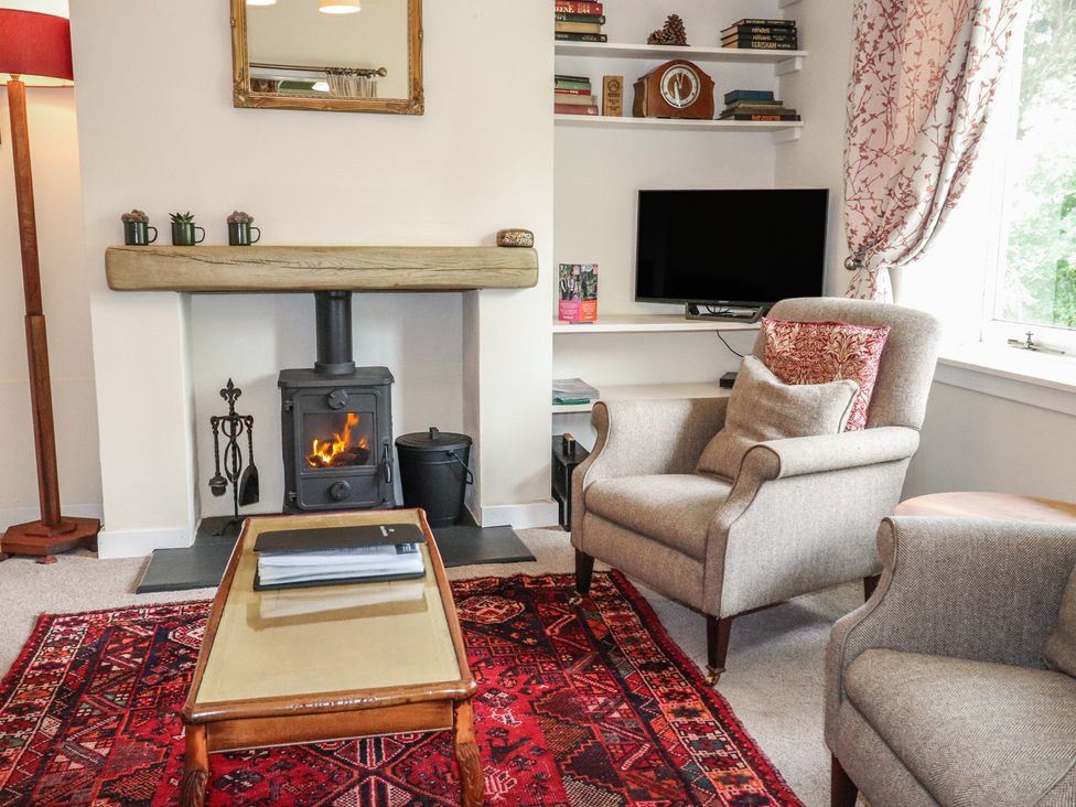 A living room with a fireplace and two chairs at Branklyn Garden Cottage in Perth