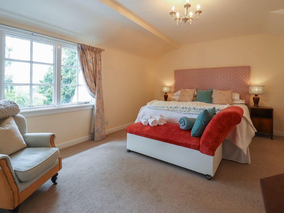 A bedroom with a large bed and armchair at Branklyn Garden Cottage Perth