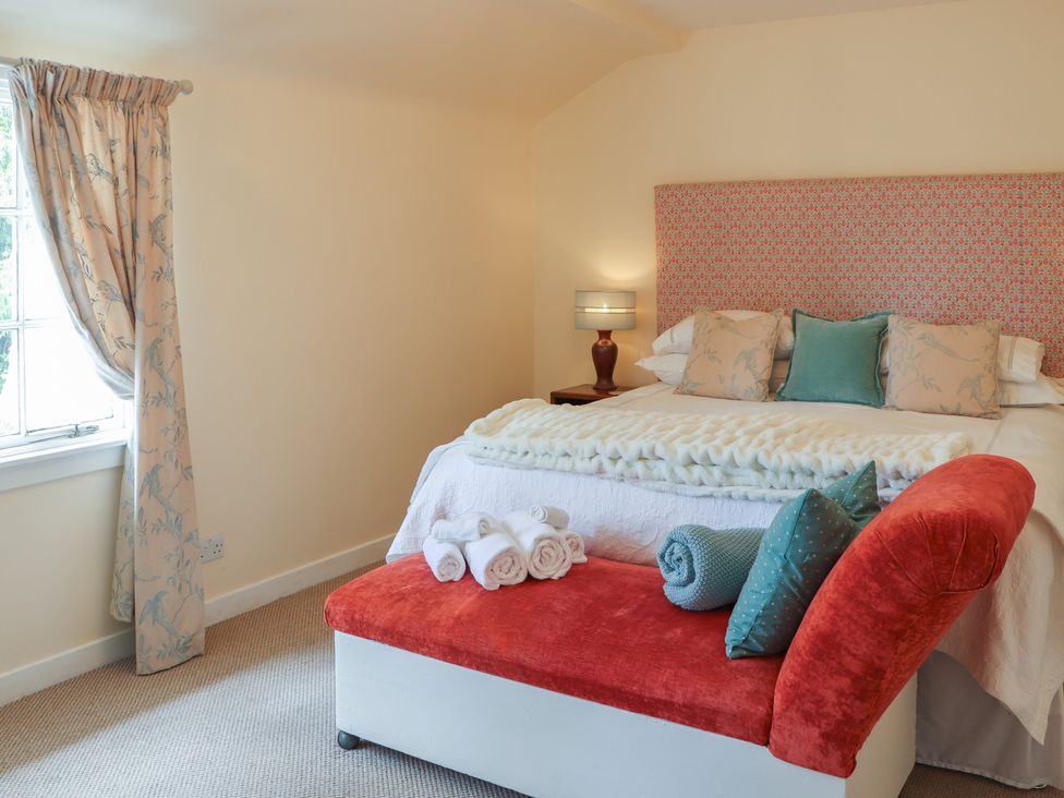 A bedroom with a bed and decorative cushions at Branklyn Garden Cottage in Perth