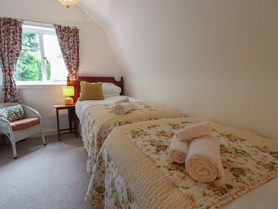 A bedroom with two beds and a chair at Branklyn Garden Cottage in Perth