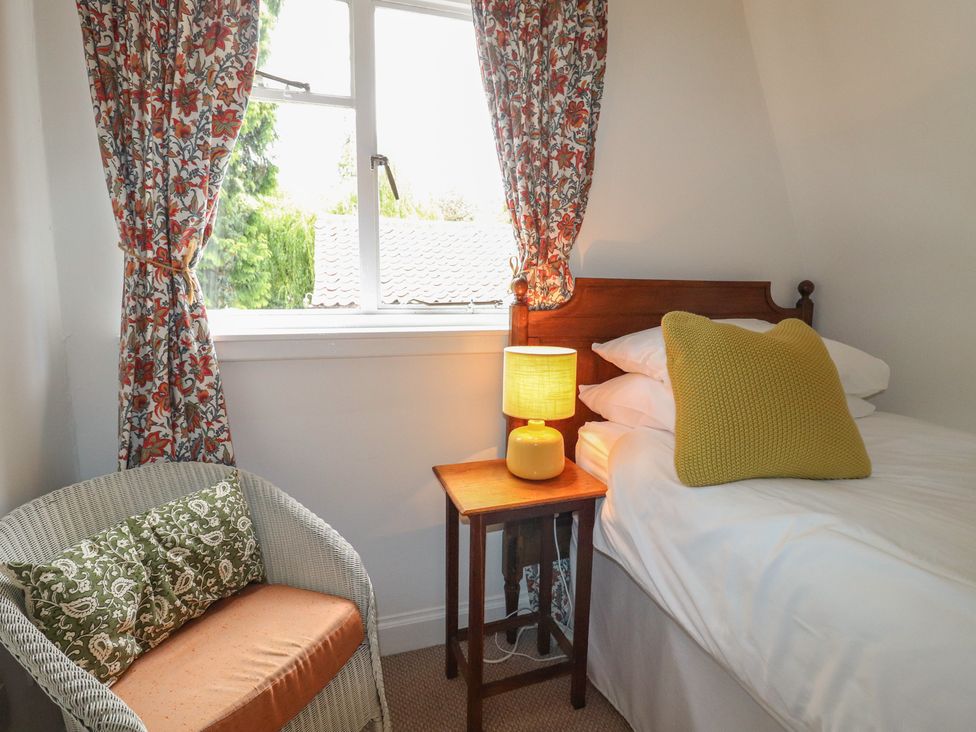 A bedroom with a single bed and a lamp at Branklyn Garden Cottage in Perth