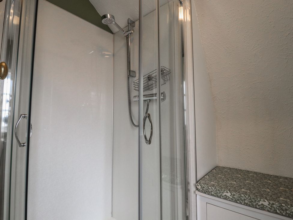 A shower with a glass enclosure and shelf at Branklyn Garden Cottage in Perth