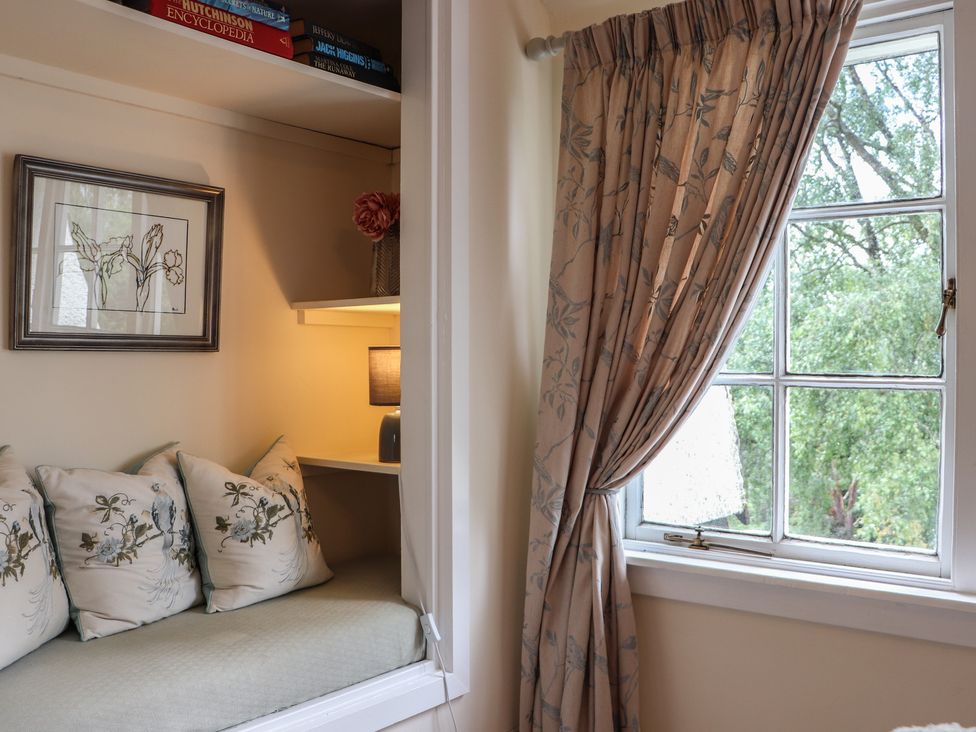 A sitting room with a window and cushions at Branklyn Garden Cottage in Perth