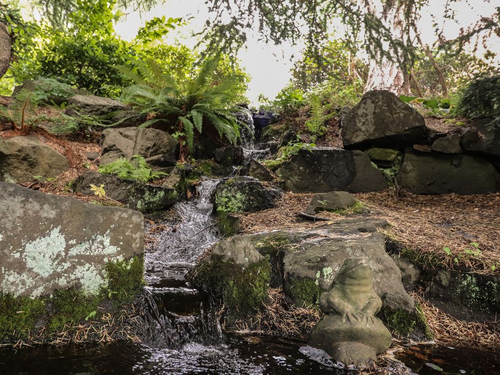 A water feature with rocks and a frog statue at Branklyn Garden Cottage in Perth