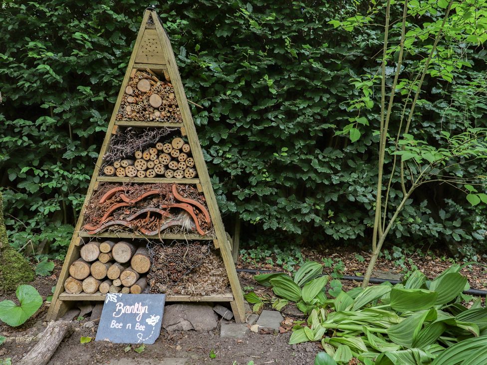 A bee hotel made of logs and twigs in a garden at Branklyn Garden Cottage Perth