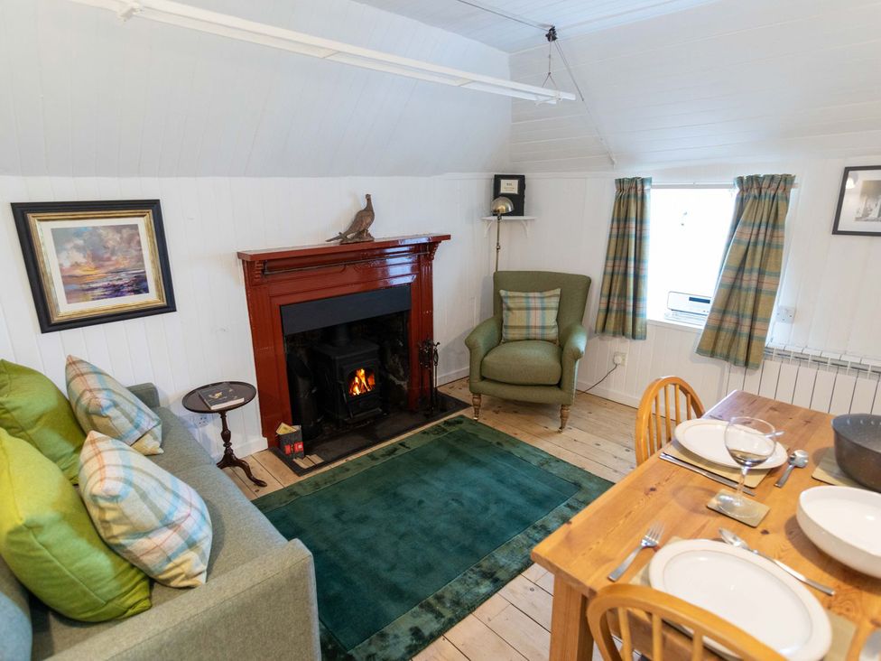 A living room with a fireplace and dining area at Beaton's Croft House - Uig Skye