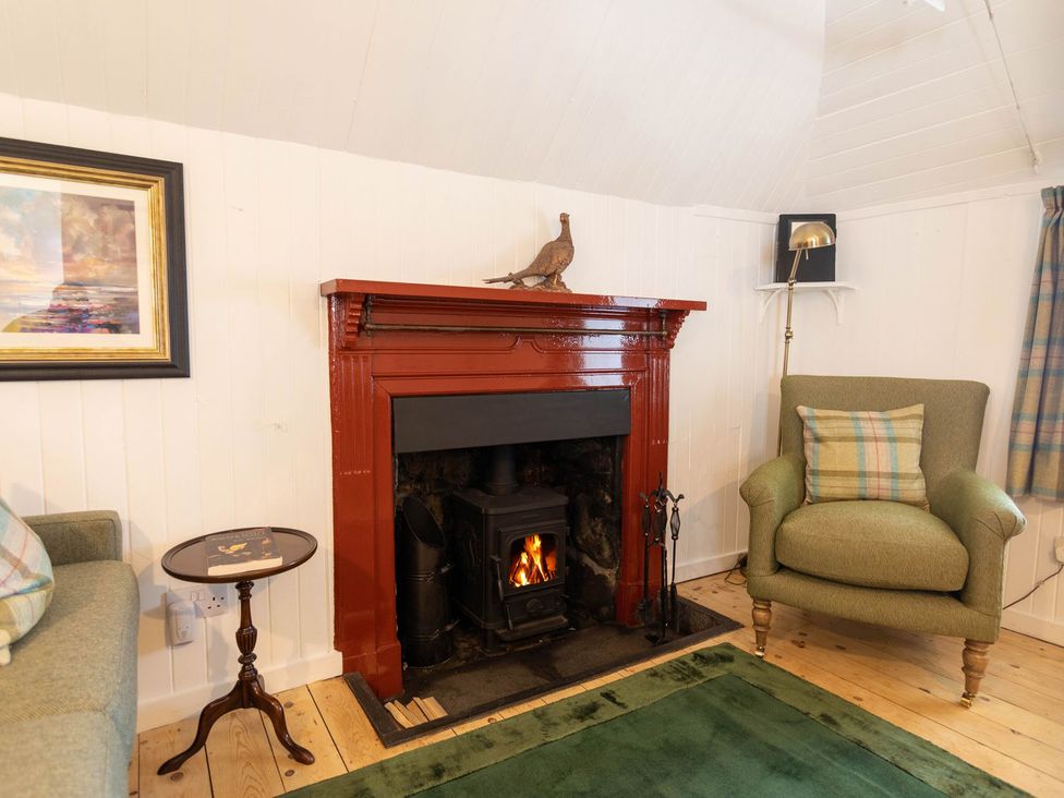 A living room with a fireplace and furniture at Beaton's Croft House - Uig Skye