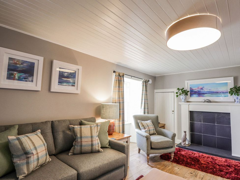 A living room with a sofa, armchair, and fireplace at Craggan Cottage - Balmacara
