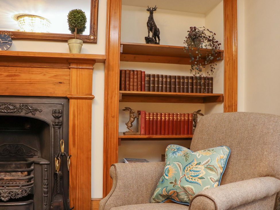 A living room with a fireplace and bookshelf at Paye House - Cromarty