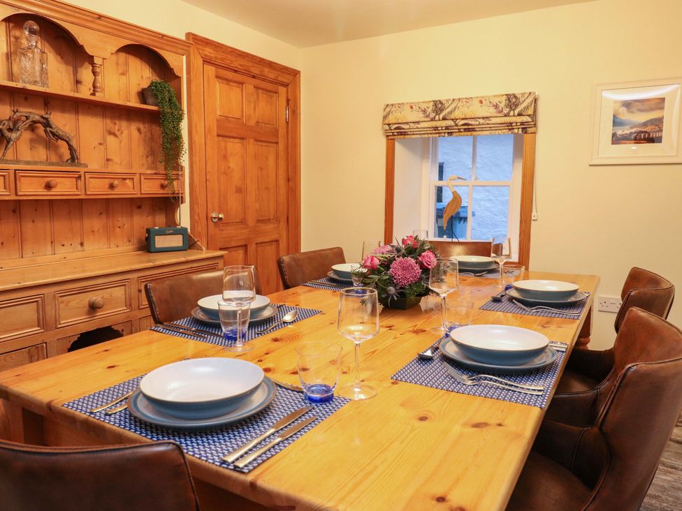 A dining room with a wooden table set for meals at Paye House - Cromarty