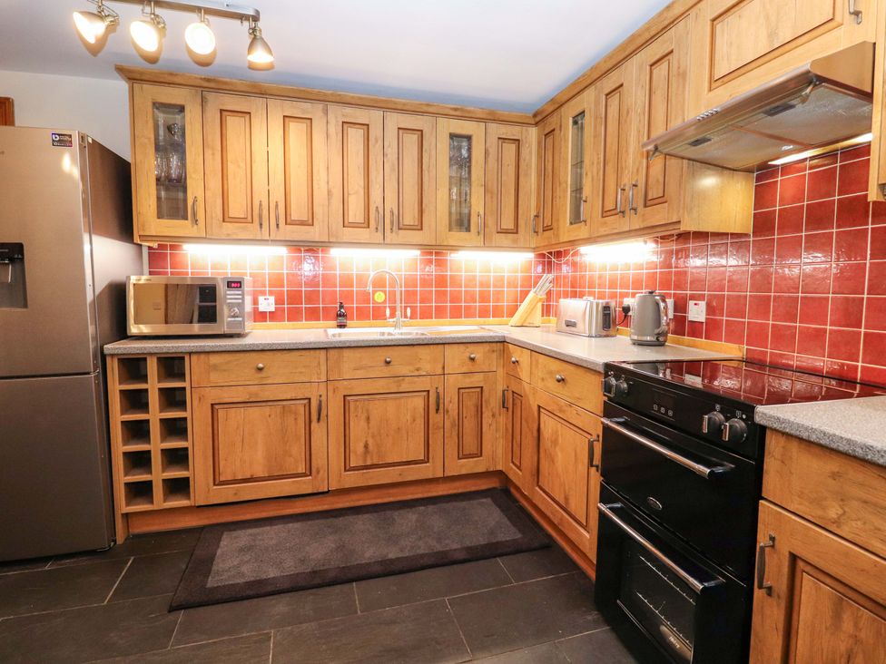 A kitchen with wooden cabinets and appliances at Paye House - Cromarty
