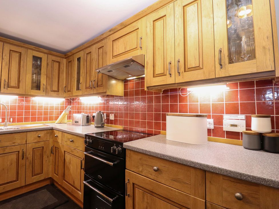 A kitchen with wooden cabinets and appliances at Paye House - Cromarty