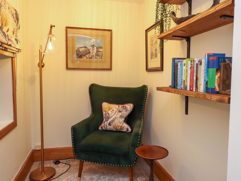 A snug with an armchair and bookshelf at Paye House - Cromarty