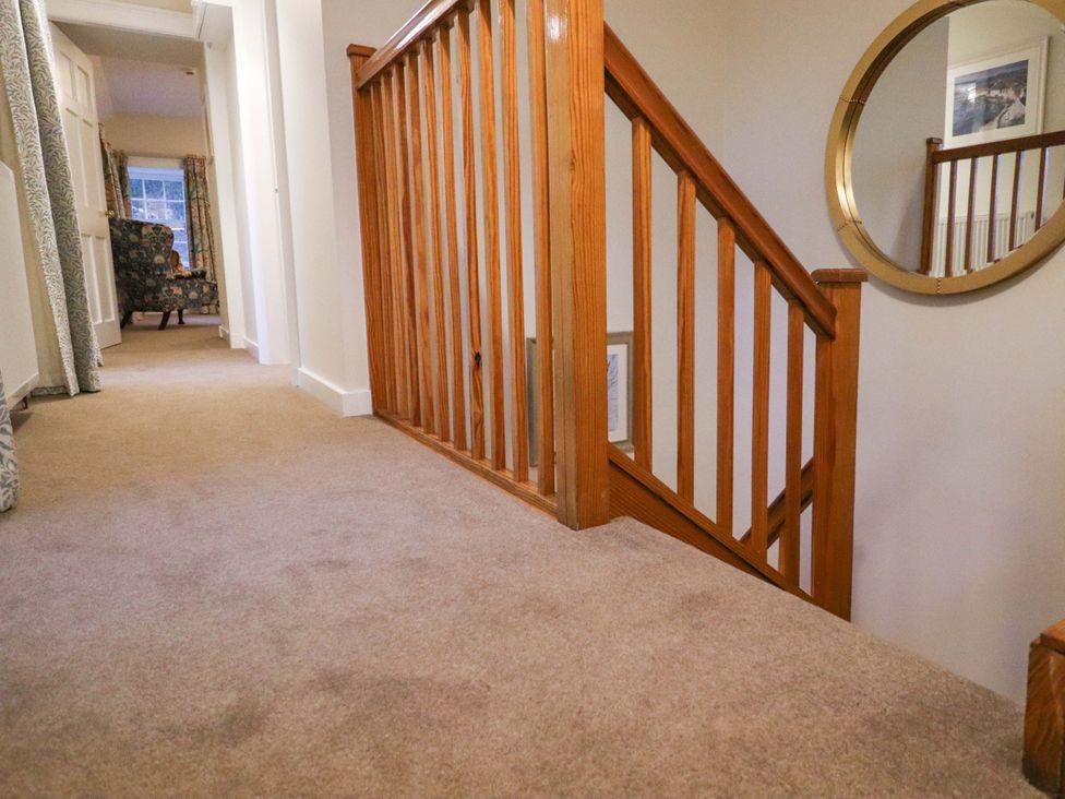A hallway with a staircase and a chair at Paye House - Cromarty