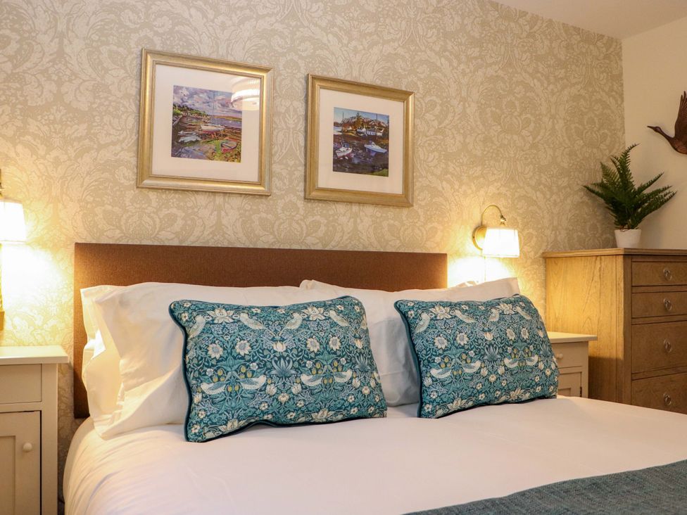 A bedroom with a bed and framed art at Paye House - Cromarty