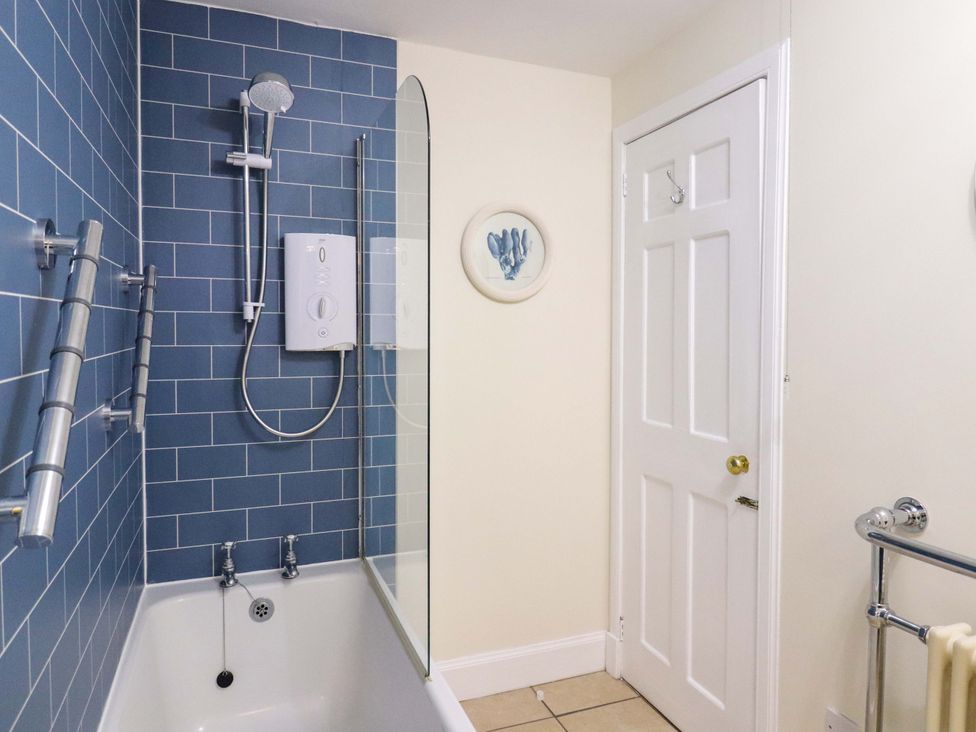 A bathroom with a shower over a bathtub at Paye House - Cromarty