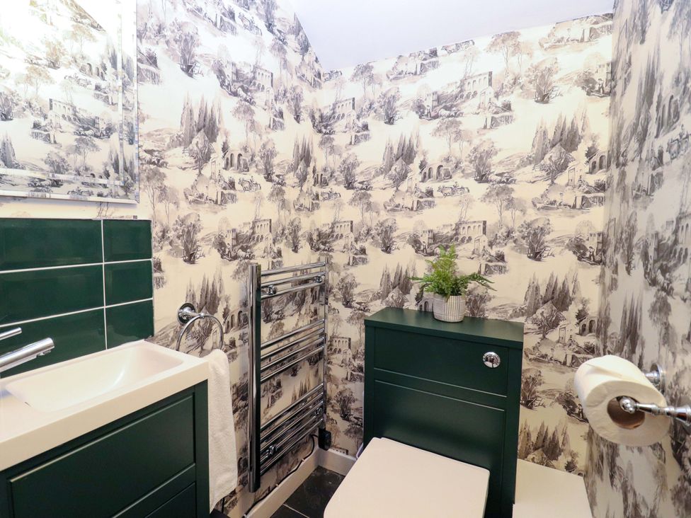 A bathroom with a sink, toilet, and decorative wallpaper at Paye House - Cromarty