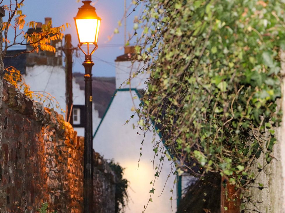 A street with a lamp post and stone wall at Paye House - Cromarty