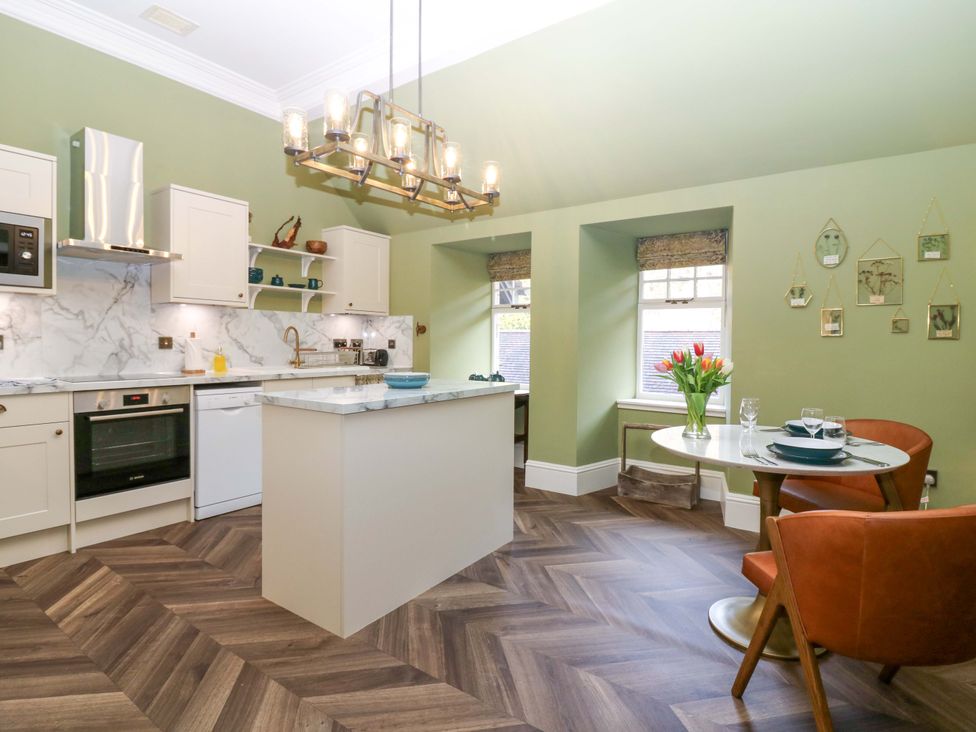A kitchen with an island, oven, and dining area at Braeriach - Mar Lodge Estate, Braemar